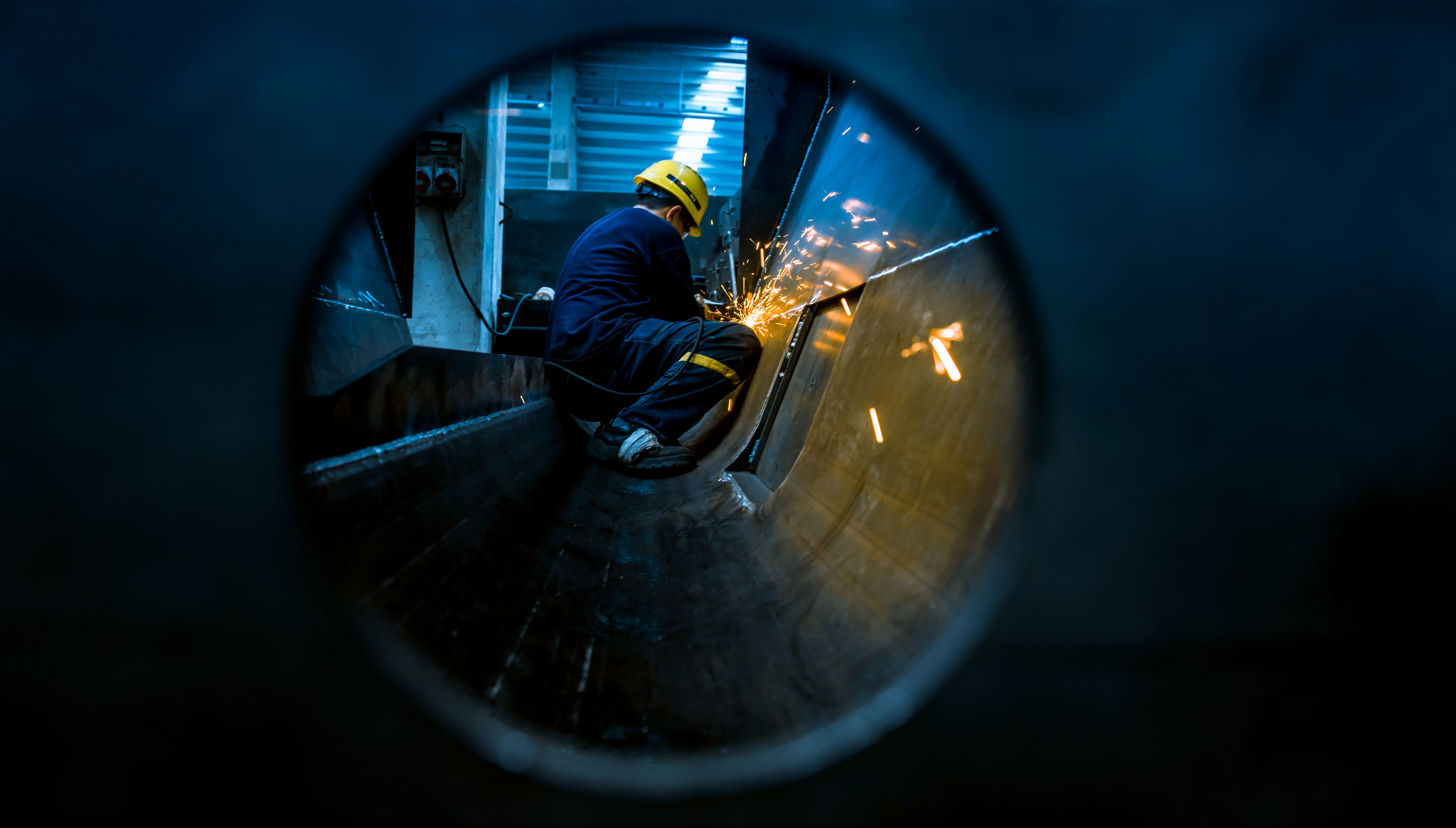 Welder at work, framed through a pipe